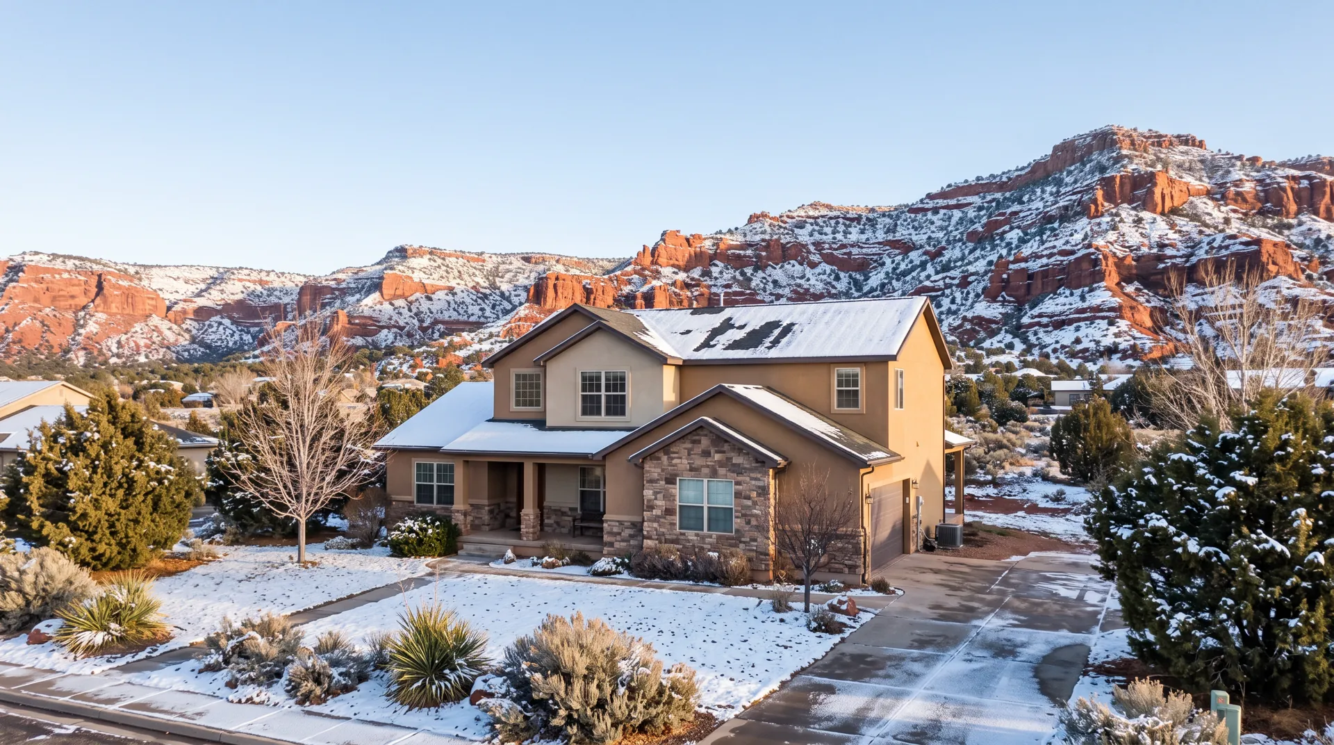 Two story stucco home with light snow in a high elevation town